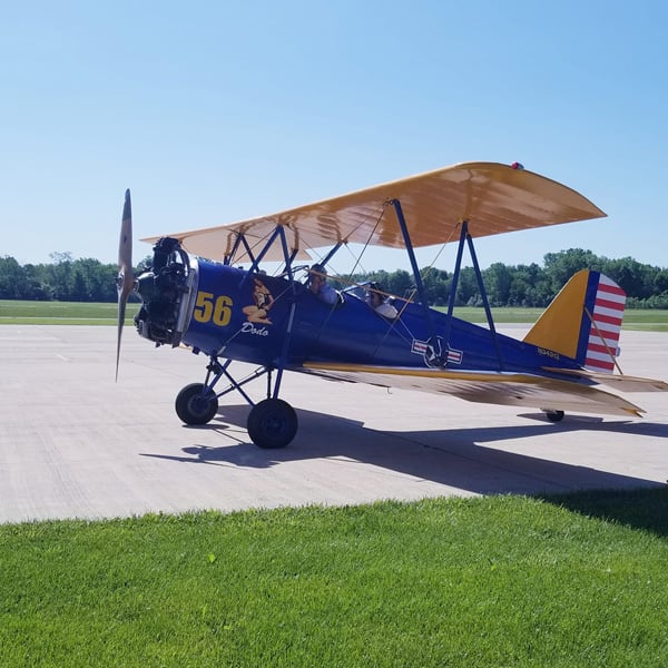 Vintage blue and yellow biplane parked on the tarmac at Michigan City Municipal Airport